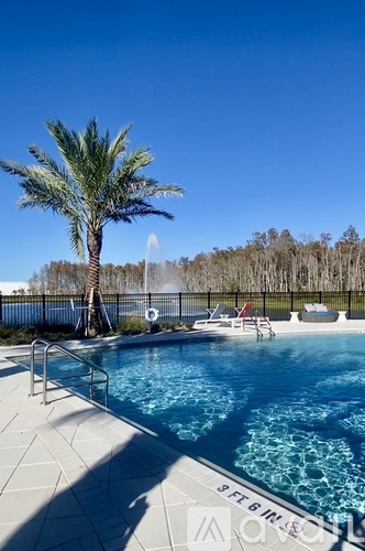 A pool with a palm tree and a fountain in the background.