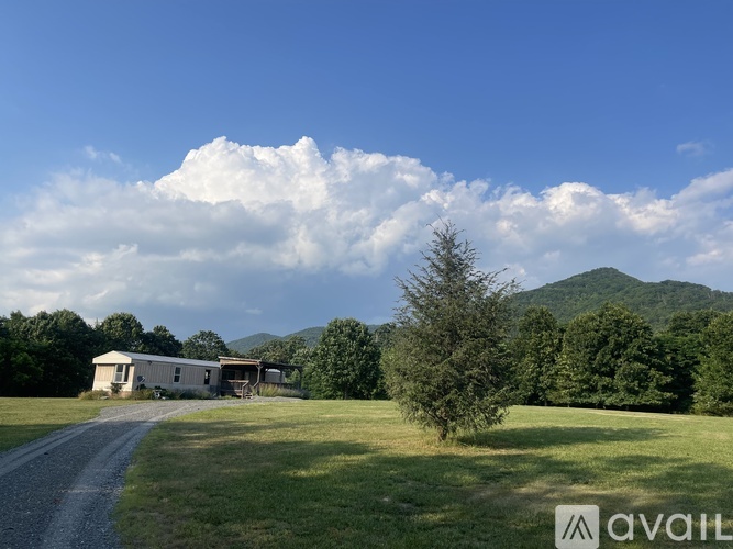A house is situated in a grassy field with a mountain in the background.
