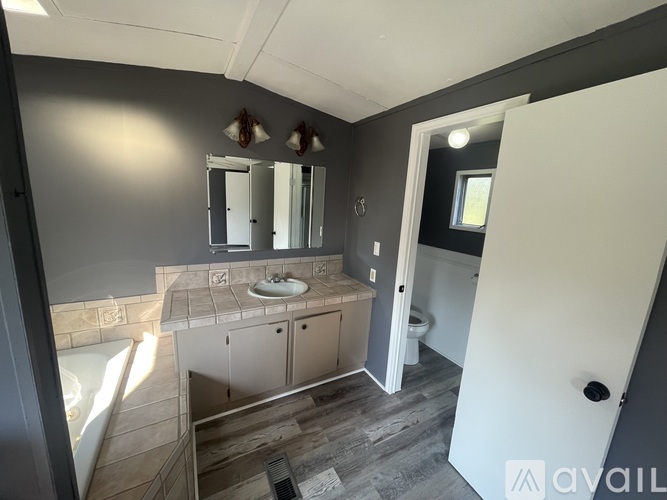 A bathroom with a tub, sink, and mirror.