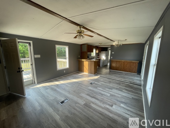 A spacious room with wooden flooring and a ceiling fan.