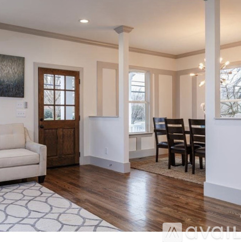 A living room with a white couch, a wooden door, and a rug.