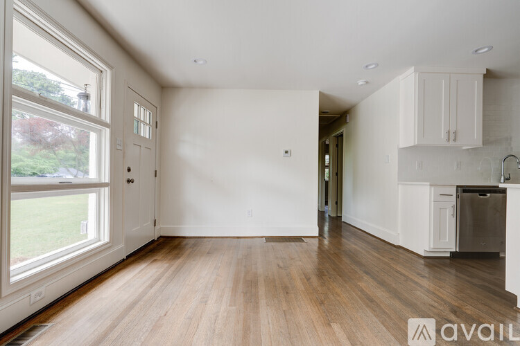 A spacious, empty room with wooden floors and white walls.