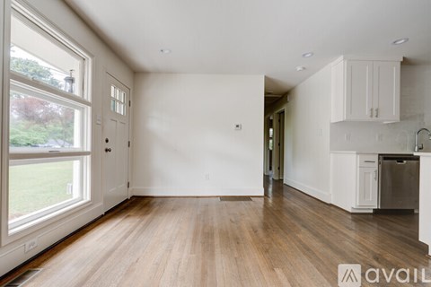 A spacious, empty room with wooden floors and white walls.
