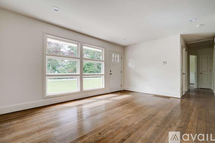 A room with wooden floors and a large window overlooking a green lawn.