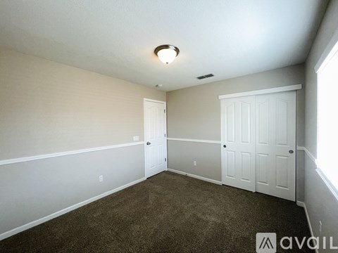 A room with carpeted floor and two white doors.