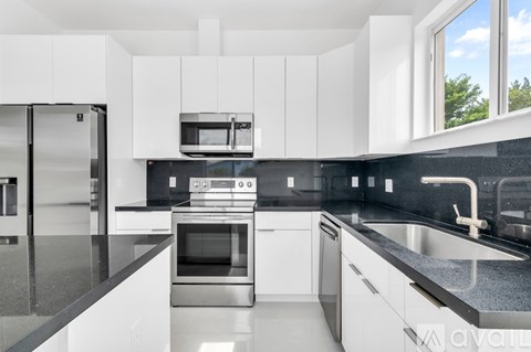 A modern kitchen with white cabinets and black countertops.