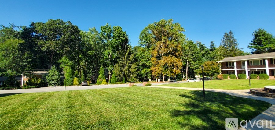 A grassy field with trees and a building in the background.