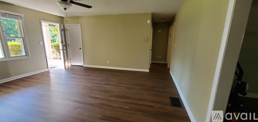 A spacious room with wooden floors and a ceiling fan.