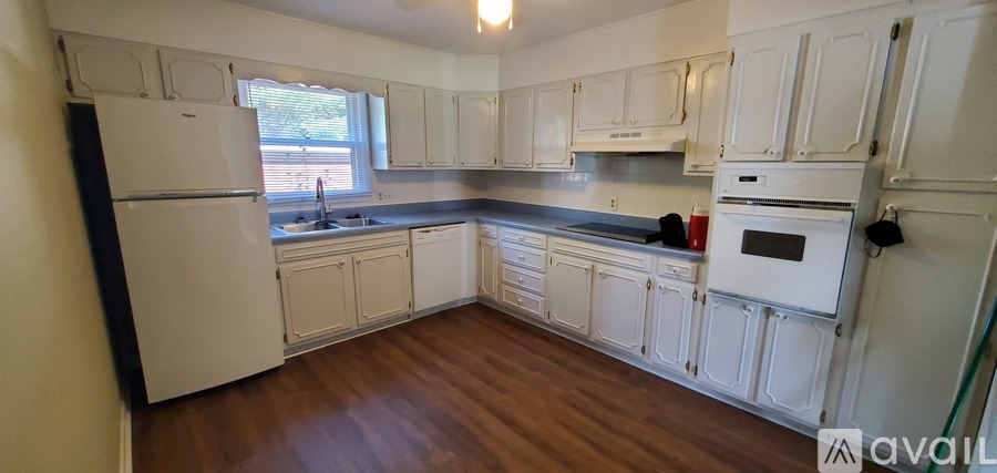 A kitchen with white cabinets and a black fridge.