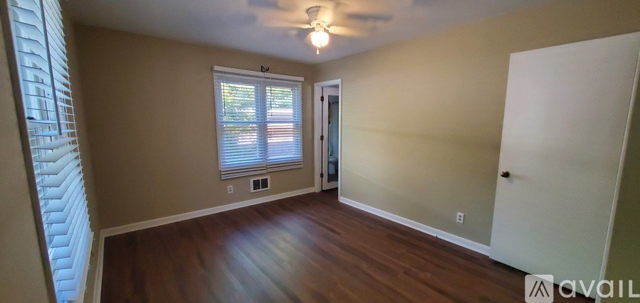 A room with wooden floors and a window with blinds.