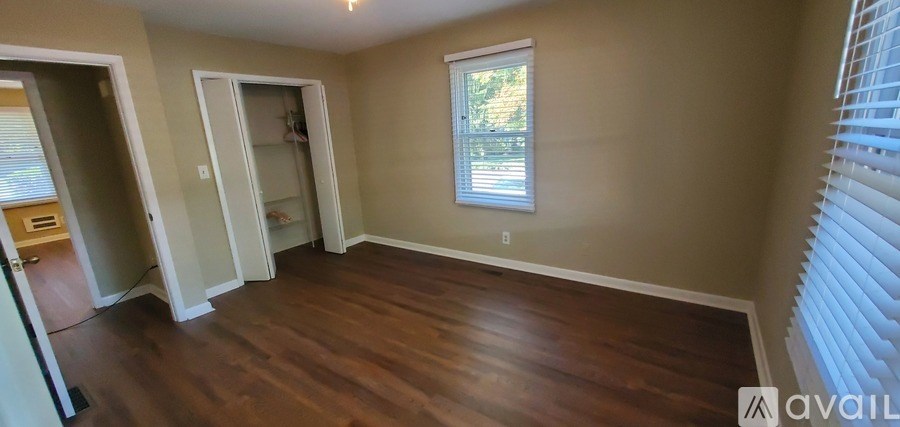 A room with a window and wooden floors is available for rent or purchase.