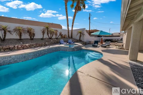 A pool surrounded by palm trees and a stone wall.