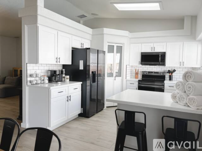 A modern kitchen with white cabinets and black appliances.