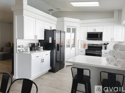 A modern kitchen with white cabinets and black appliances.