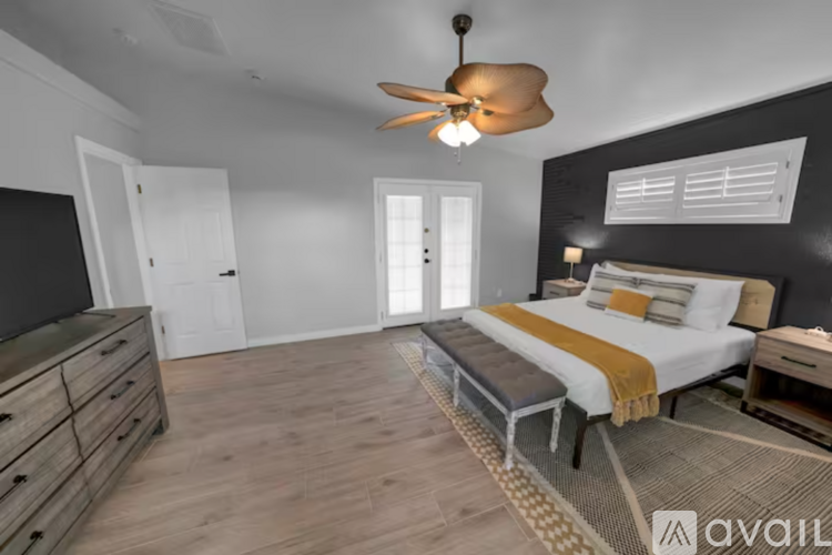 A bedroom with a bed, dresser, and ceiling fan.
