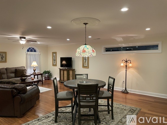 A dining room with a round table and chairs, a couch, and a ceiling fan.