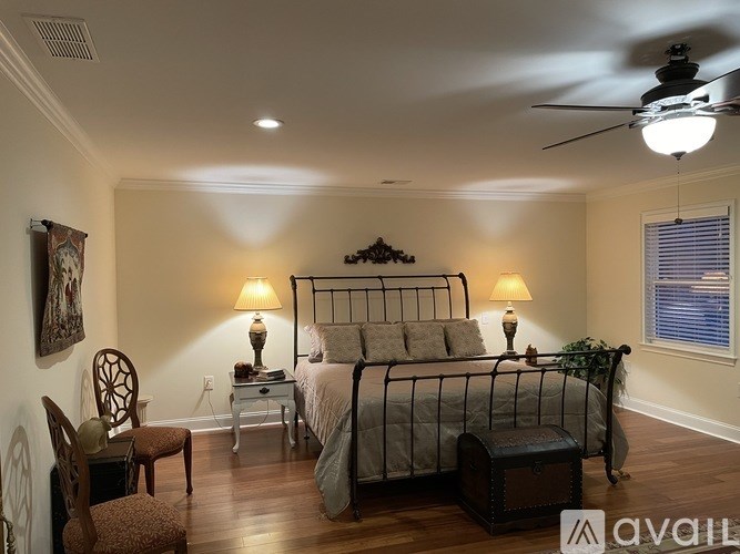 A bedroom with a bed, chair, and lamp.