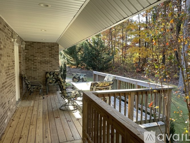 A wooden deck with a bench and a table is surrounded by trees.