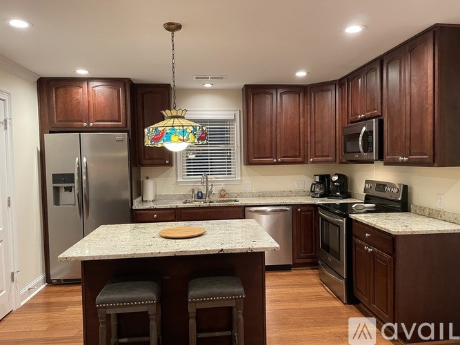 A kitchen with brown cabinets and a marble countertop.