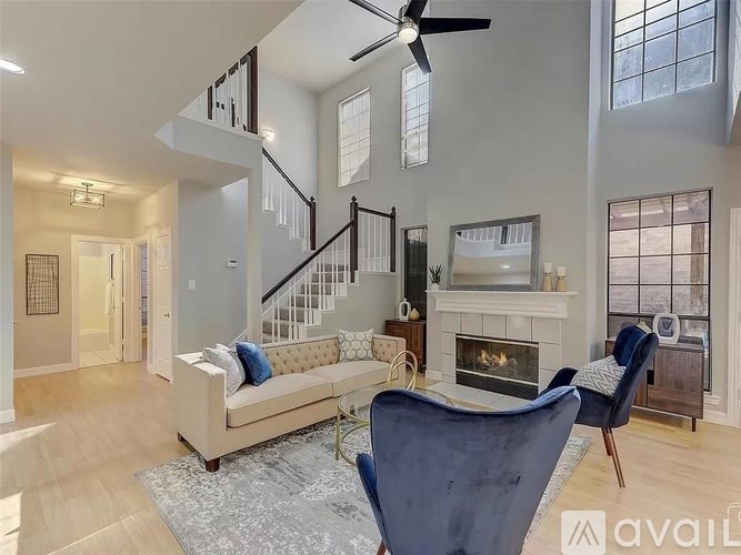 A living room with a couch, a chair, a fireplace, and a staircase.