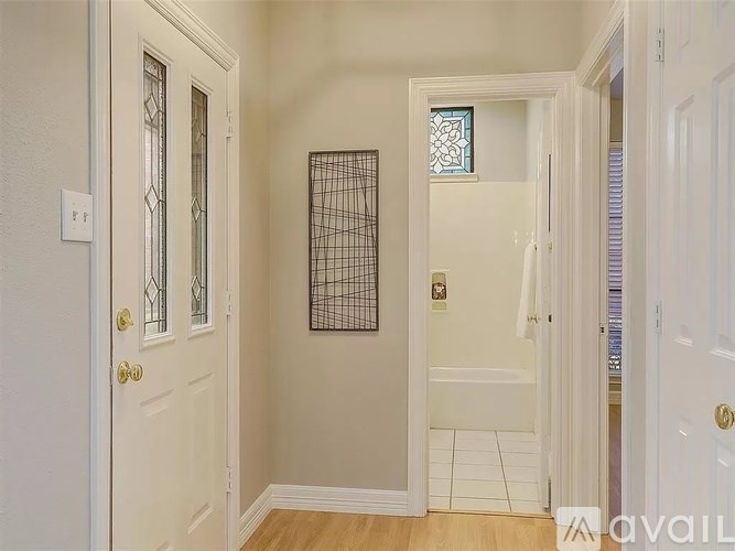 A white door with a gold handle is on the left of a hallway.