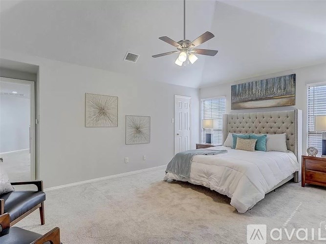 A bedroom with a large bed and a ceiling fan.