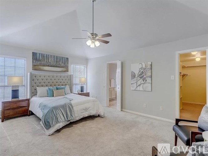 A bedroom with a large bed and a ceiling fan.