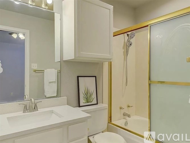A bathroom with a sink, mirror, toilet, and a shower with a glass door.
