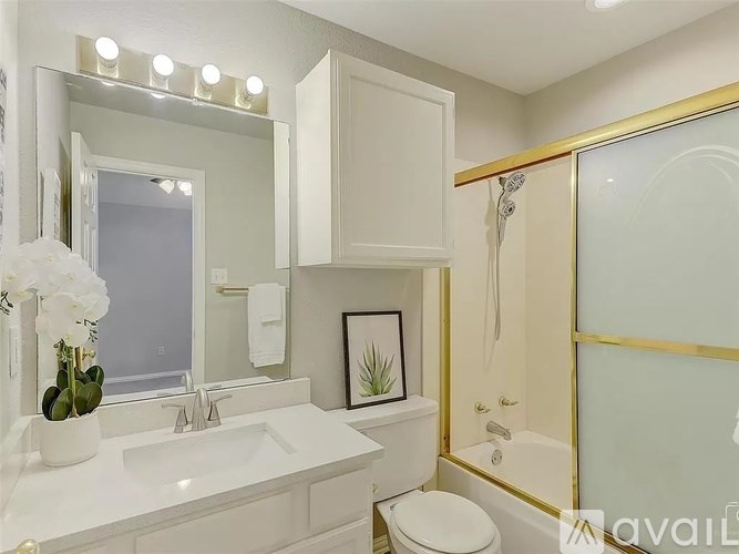 A white bathroom with a sink, toilet, and a mirror.