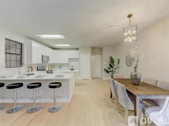 A modern kitchen with white cabinets and a wooden dining table.