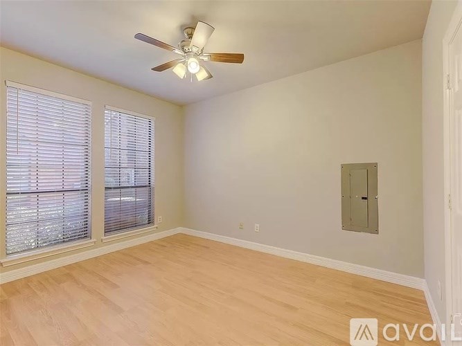 A room with a ceiling fan and sliding glass doors.