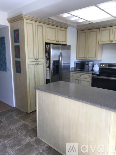 A kitchen with a refrigerator, microwave, and oven.