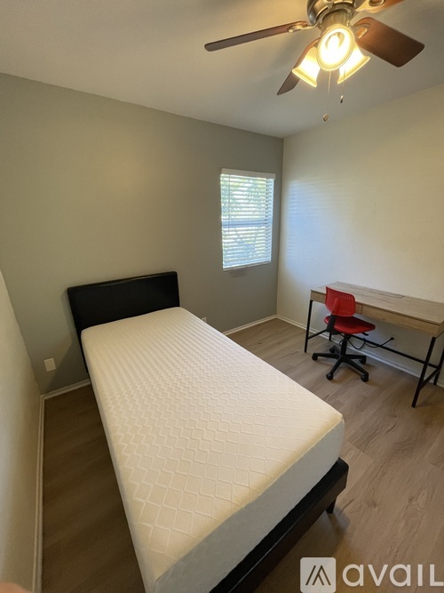 A bedroom with a bed, desk, and chair.