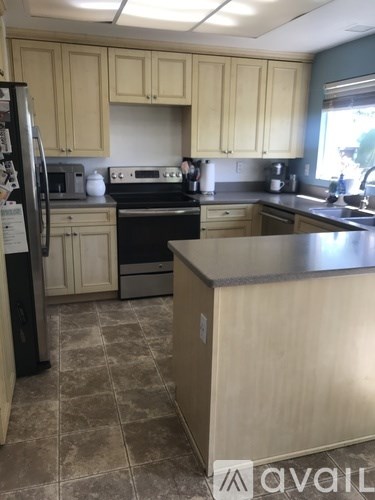 A kitchen with wooden cabinets and a black fridge.