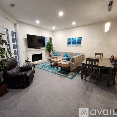 A living room with a grey couch, a black leather chair, a wooden coffee table, and a television.