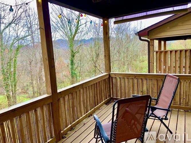 A wooden deck with two chairs and a view of the forest.