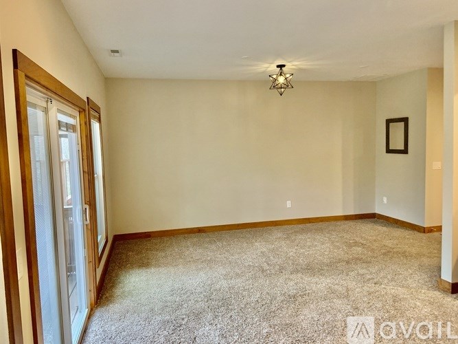 A room with a carpeted floor, a ceiling light, and a picture frame on the wall.