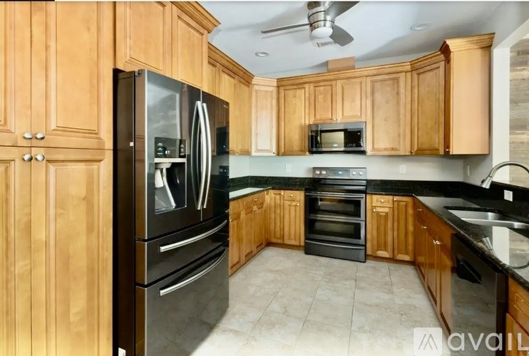 A kitchen with wooden cabinets and a black fridge.
