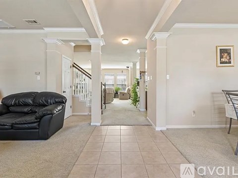 A living room with a black leather sofa and a carpeted floor.