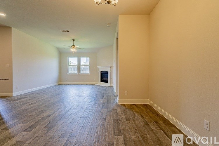 A spacious room with wooden flooring and a ceiling fan.