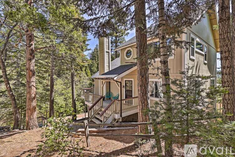 A house surrounded by trees with a balcony and a staircase leading to the entrance.