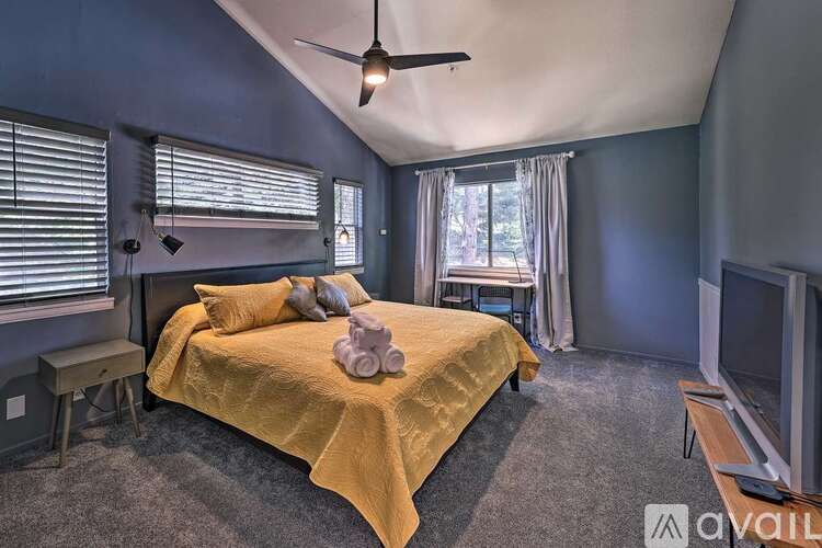 A bedroom with a bed covered in a yellow blanket and a ceiling fan.