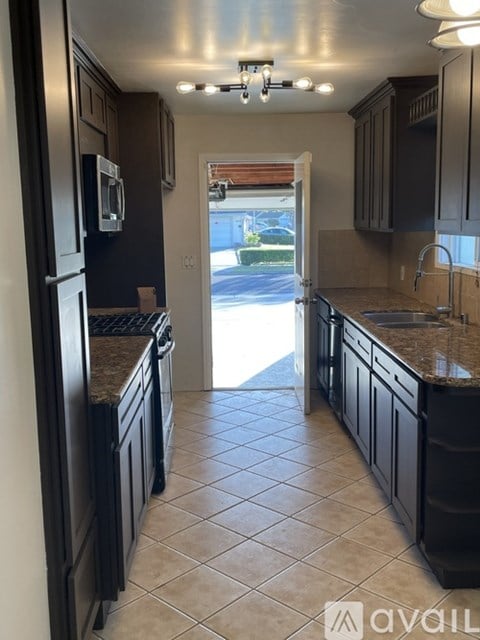 A kitchen with black cabinets and a tiled floor.