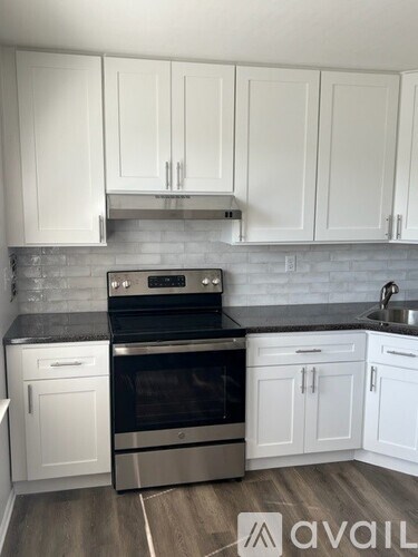 A kitchen with white cabinets and a black stove top oven.