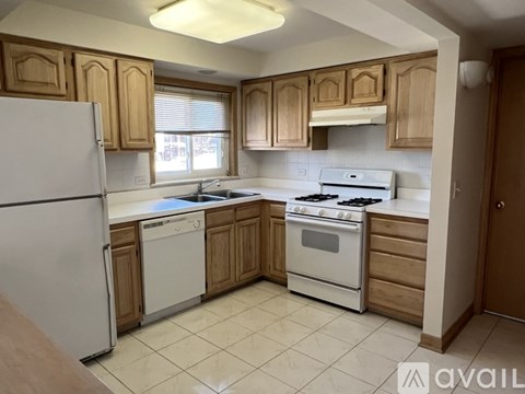 A kitchen with white appliances and wooden cabinets.