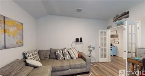 A living room with a grey couch and a painting on the wall.