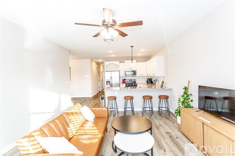 A living room with a brown couch and a ceiling fan.
