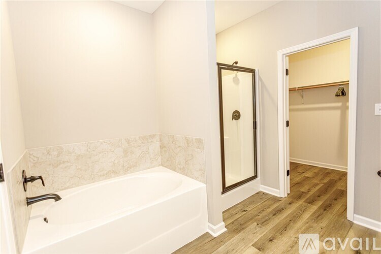 A bathroom with a white tub and wooden floors.