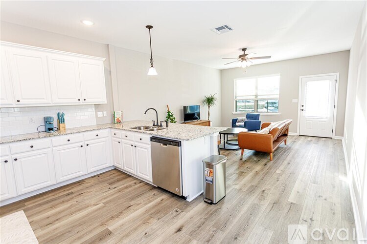 A kitchen with white cabinets and a wooden floor.