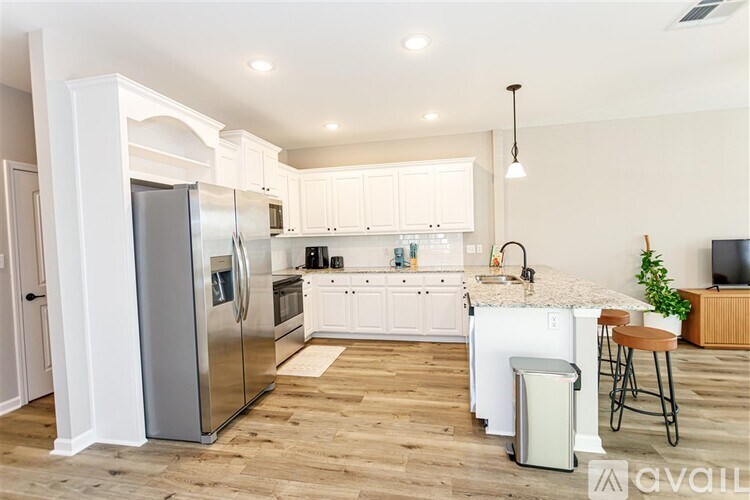 A kitchen with a refrigerator, oven, and a counter with a plant on it.